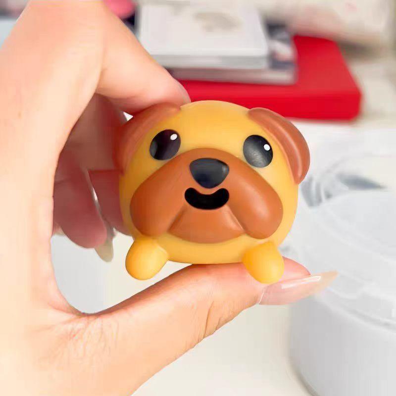 Fingers gently pressing the top of the tiny pug toy to activate its tongue